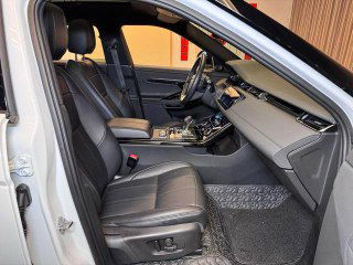 Передние сиденья Range Rover в чёрной кожаной обивке, вид со стороны открытой двери; показаны регулировки и пространство для водителя