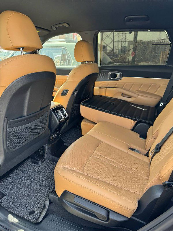 Задний ряд сидений KIA Sorento: бежевые кожаные сиденья, простор для пассажиров и вид задней части салона, подготовленного для семейных поездок.