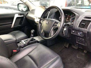 Салон Toyota Prado 2021, передняя панель, руль и центральная консоль, чёрная отделка кресел и приборная панель на осмотре.