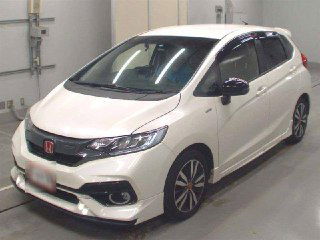 Белый Honda FIT 2017, вид спереди и сбоку на осмотровой площадке, автомобиль представлен в доступных к приобретению лотах.
