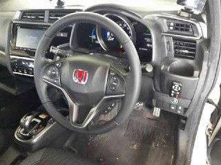 Салон Honda FIT 2017, руль, приборная панель и центральная консоль с видимыми элементами управления и центральным экраном.