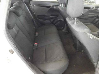 Задние тканевые сиденья Honda FIT 2017, общий вид салона с задней лавкой и ремнями безопасности на проверочной площадке.