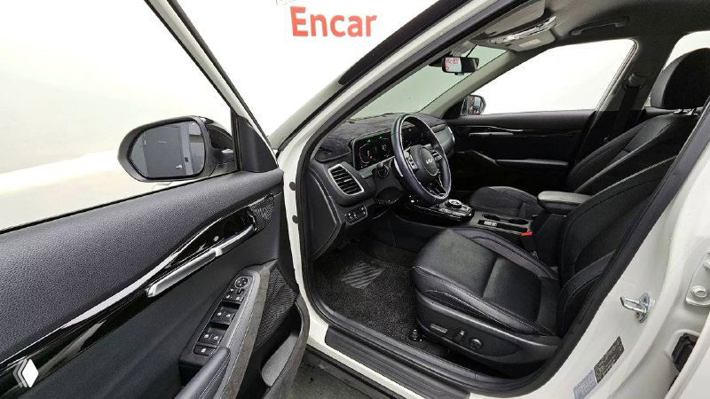 Открытая передняя дверь KIA Seltos 2022 — вид на водительское сиденье и дверную панель; показывает пространство и состояние обивки салона.