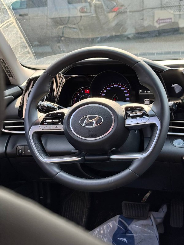 Крупный план руля и приборной панели Hyundai Avante (Elantra) 2021: мультируль, приборная панель и органы управления на фоне салона.