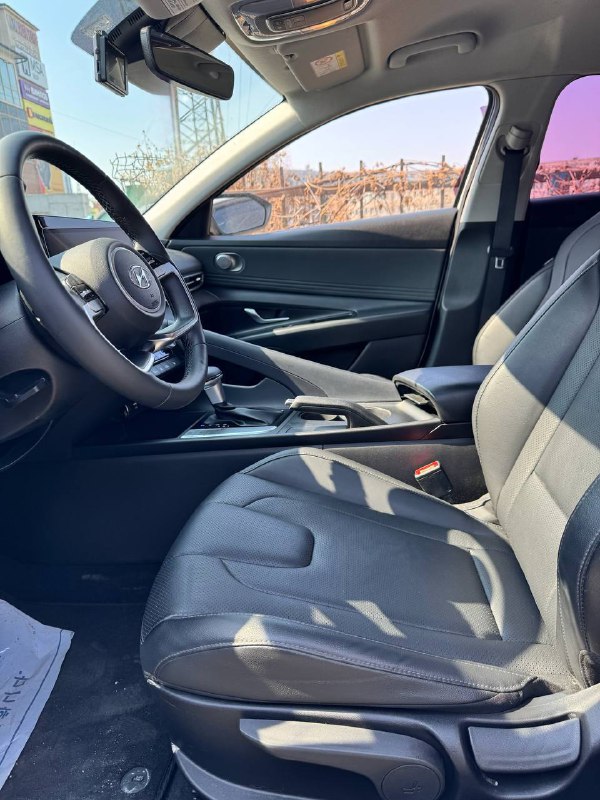 Сиденье водителя и часть передней панели Hyundai Avante (Elantra) 2021 — показаны тканевые кресла, подлокотник и общий вид интерьера.