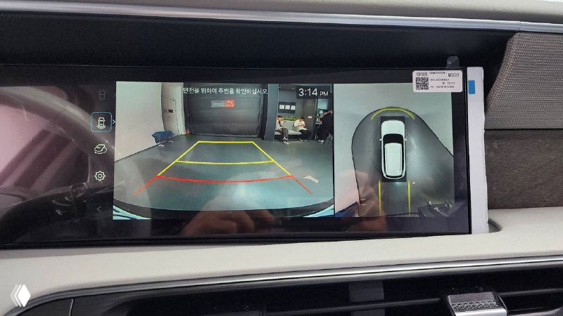 Экран мультимедиа Hyundai Palisade 2025 показывает изображение с камеры заднего вида и разметку парковки, демонстрируется система помощи