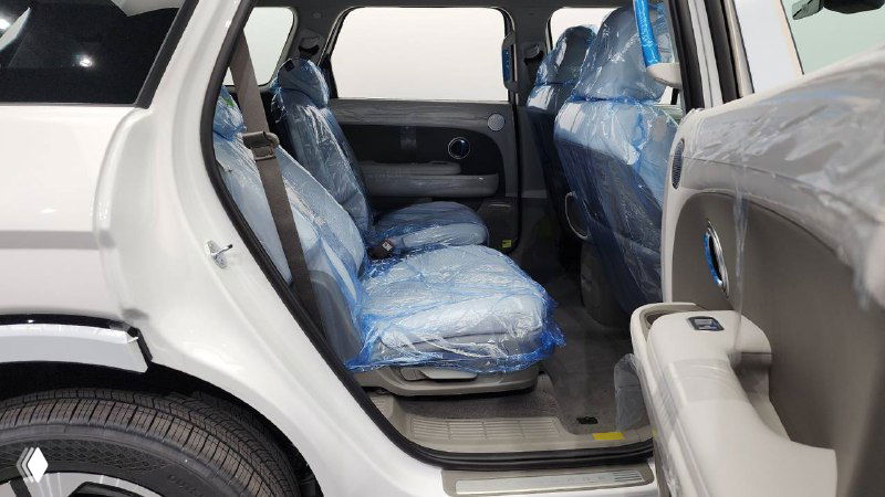 Второй ряд сидений Hyundai Palisade 2025 в упаковочной пленке, пространство между сиденьями и дверь, показаны 7 посадочных мест