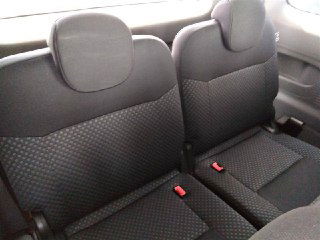 Крупный план второго ряда сидений Nissan NV200 — два посадочных места с ремнями безопасности, состояние и текстура обивки на фото.