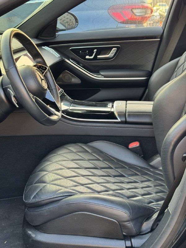 Переднее сиденье Mercedes S 350d с чёрной кожей и ромбовой прострочкой, вид салона, дверная панель и элементы управления сиденьем.