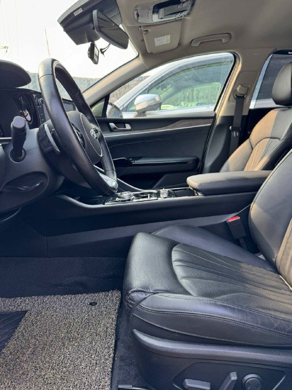 Вид на передние сиденья и центральный туннель KIA K5 — кожаная обивка, регулировки сидений и часть салона со стороны пассажира.