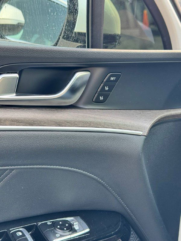 Деталь дверной панели KIA K5: кнопки памяти сидений, декоративная вставка под дерево и элементы управления стеклоподъёмниками.