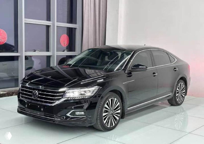 Боковой профиль Volkswagen Passat, чёрный седан на белом полу шоурума — видно линии корпуса, колёсные диски и общую геометрию автомобиля.