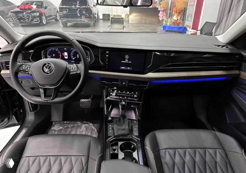 Интерьер Volkswagen Passat — широкая панель приборов, мультисенсорный экран, руль и декоративная подсветка в салоне автомобиля на фото.