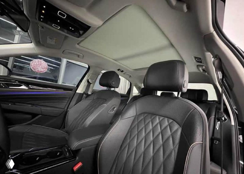 Общий вид салона с потолком и передними сиденьями Passat, видно панорамную крышу, потолочную обивку и внутреннее освещение салона автомобиля.