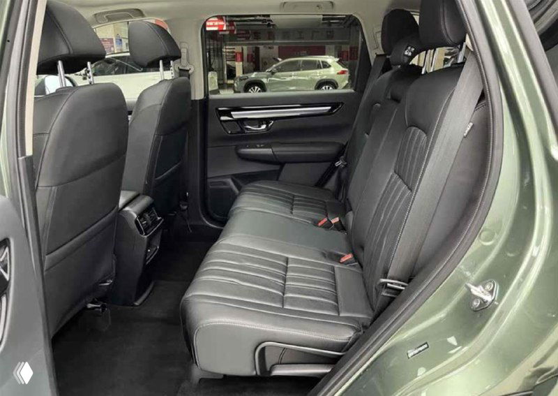 Задний ряд сидений Honda Breeze, чёрная обивка; видно пространство для ног, подголовники и дверную панель салона на фото в салоне.