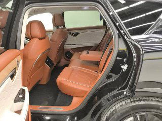 Вид на задние сиденья Voyah Free через открытую заднюю дверцу: коричневые кожаные кресла, простор для ног и элементы отделки дверей.