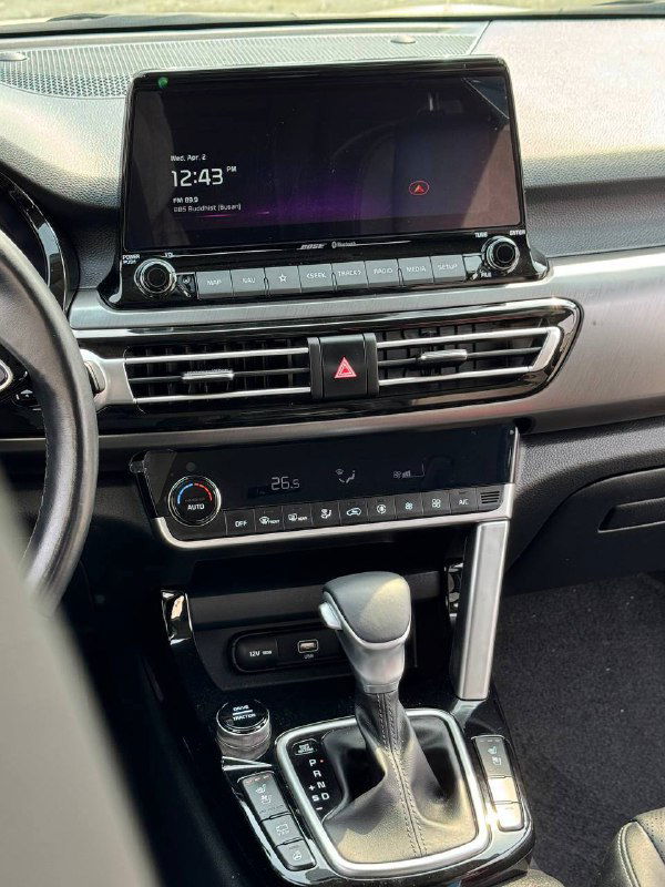 Центральная консоль KIA Seltos с экраном мультимедиа, климат-контролем и кнопками управления — детальный кадр панели приборов и экрана.