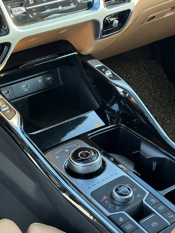 Центральная консоль и селектор у KIA Sorento Prestige — крупный план панели управления, подстаканники и отделка глянцевым пластиком.