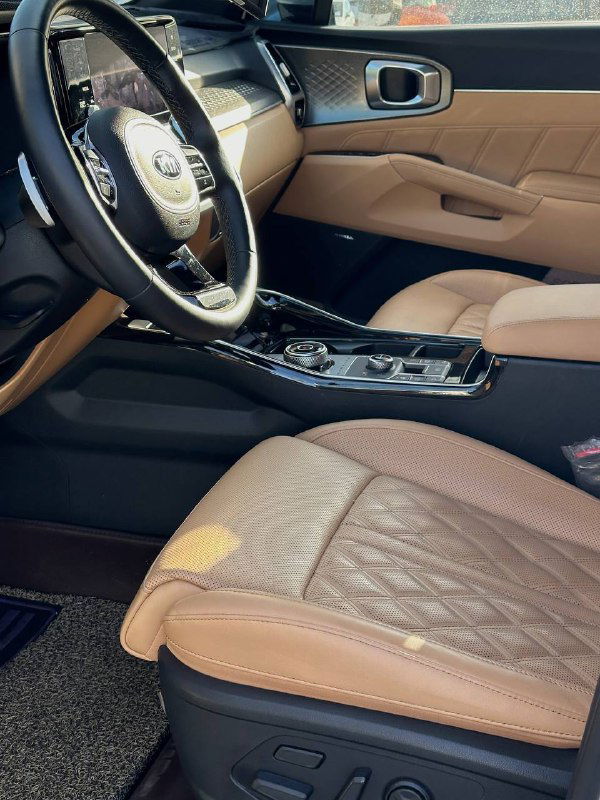 Руль и передние сиденья KIA Sorento с отделкой бежевой кожи — вид на водительское место и часть салона в профиль.