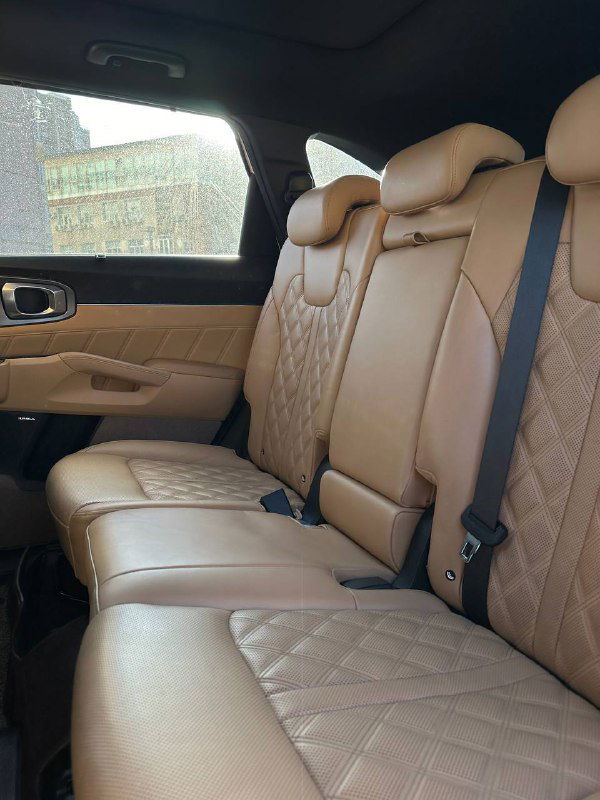 Задний ряд сидений KIA Sorento — бежевые кожаные сиденья, ремни безопасности и простор в салоне на заднем ряду.