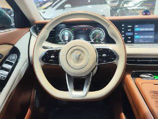 Руль Voyah Free вблизи с видимыми шкалами приборов на цифровой панели, коричнево‑белая отделка салона и элементы управления на руле.