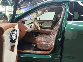 Открытая передняя дверь Voyah Free: видны фронтальное сиденье в коричневой отделке, пластик защитной плёнки и дизайнерские детали внутренней панели.