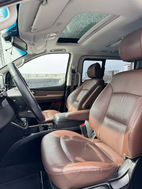 Интерьер Hyundai Starex с коричневой кожаной отделкой сидений и панорамным люком, вид спереди-назад через передние сиденья.