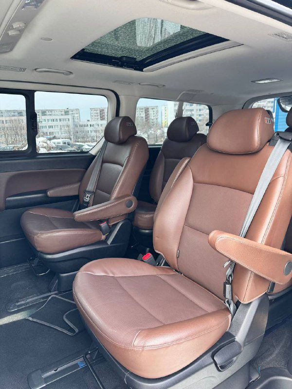 Второй ряд сидений Hyundai Starex с коричневой кожей, вид сбоку на раздельные капитанские кресла и просторный салон минивэна.