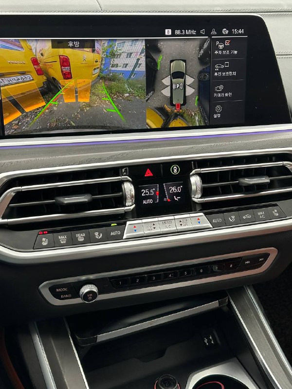 Деталь центральной консоли BMW X7 с экраном мультимедиа и элементами климат-контроля — крупный план дисплея и кнопок управления.