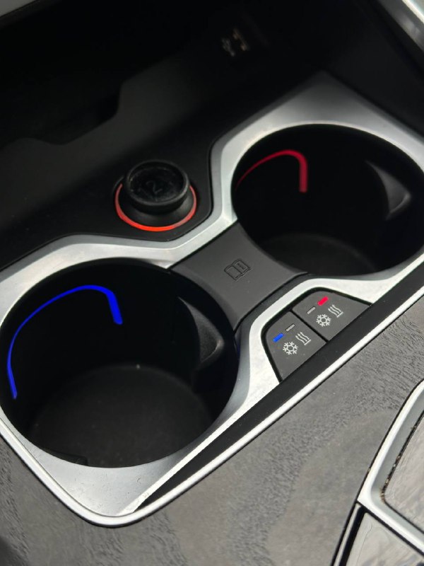 Фрагмент передней части центрального тоннеля BMW X7: подстаканники, подсветка и органы управления рядом с селектором передач.