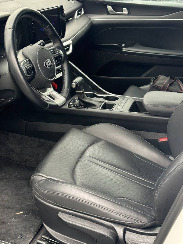 Интерьер KIA K5: вид на рулевое колесо, панель приборов и сиденье водителя, состояние обивки и рулевого управления при осмотре.