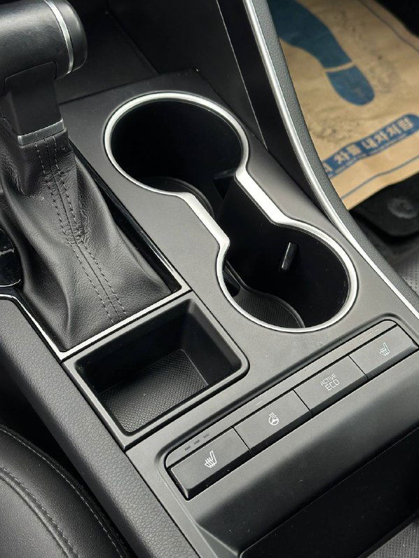 Крупный план центральной консоли KIA K5: подстаканники, селектор АКПП и кнопки управления, подтверждение целостности элементов салона.