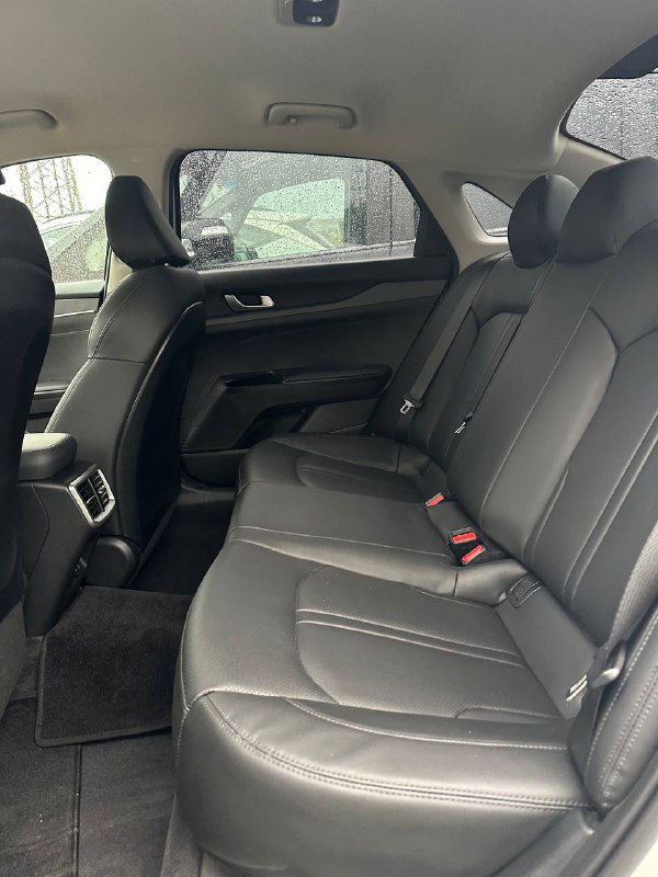 Задний ряд сидений KIA K5 с чёрной кожаной обивкой: три посадочных места, состояние подлокотника и пространства для ног при осмотре.