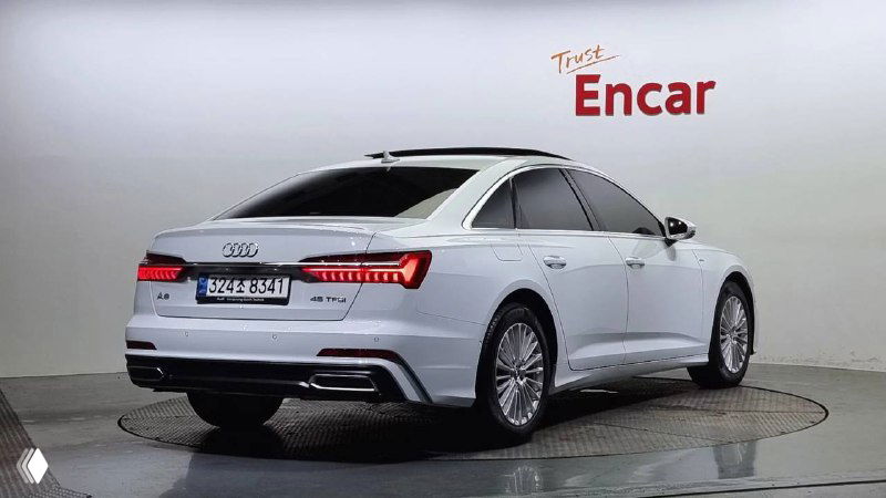 Белый Audi A6 45 TFSI, вид сзади и в три четверти на поворотной площадке автосалона Encar; кадр показывает заднюю оптику, бампер и общую сохранность кузова автомобиля