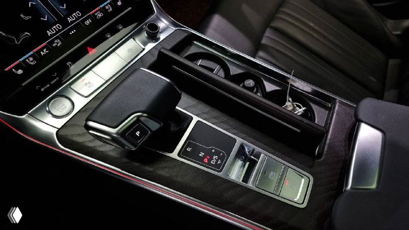 Ближний план селектора передач и подлокотника Audi A6, демонстрирующий отделку, расположение розеток и ниши для мелких предметов в центральной консоли автомобиля