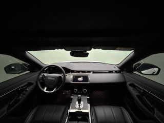 Панорамная фотография приборной панели и центральной консоли Range Rover Evoque с экраном мультимедиа и кожаной отделкой салона, вид спереди.