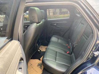 Задний ряд второго Range Rover Evoque, чёрная кожаная отделка, вид через приоткрытую заднюю дверь на пол и сиденья, демонстрация состояния салона.