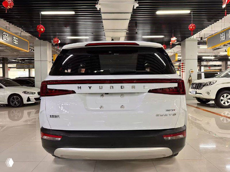 Задняя часть белого Hyundai Custo 2022 в автосалоне: вид багажника и задних фонарей, крупно видна надпись HYUNDAI на крышке багажника и отделка бампера.