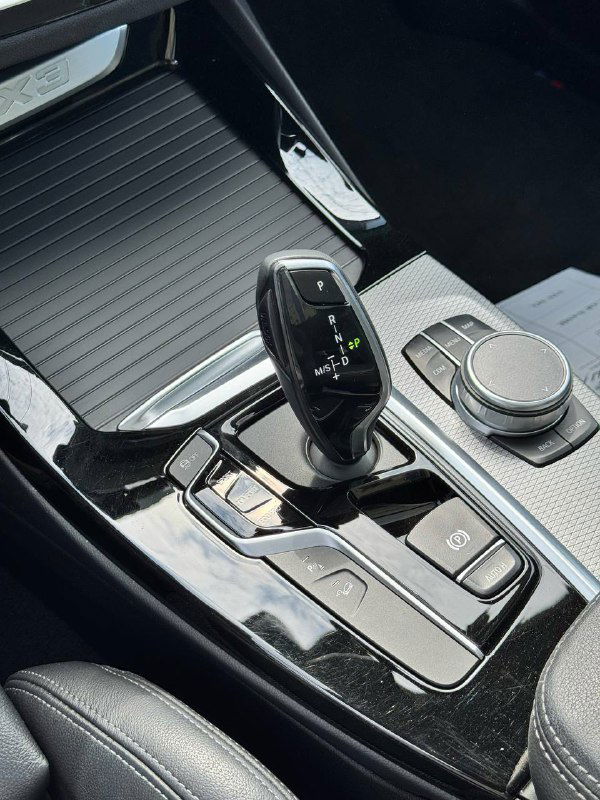 Селектор передач и элементы управления на центральном тоннеле BMW X3, вид на зону между сиденьями и ручку КПП