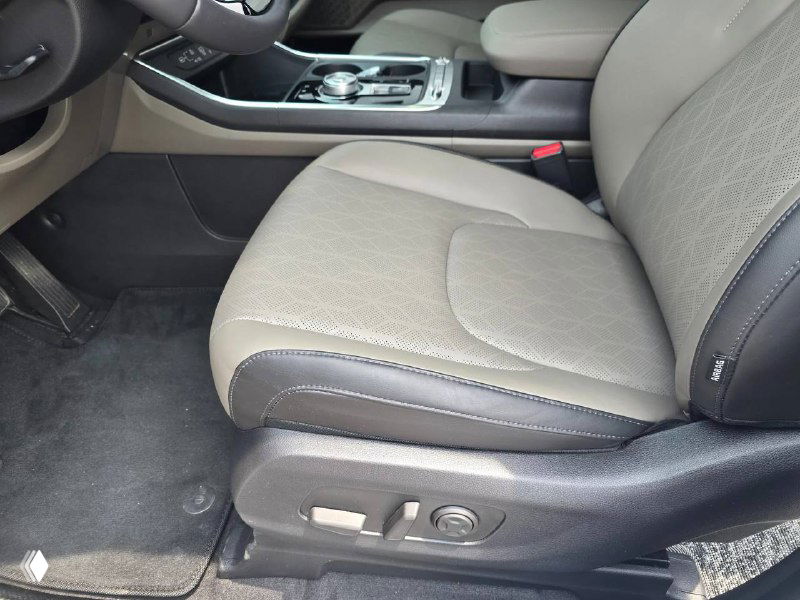 Переднее сиденье KIA Carnival 2024 — крупный план водительского кресла с тканевой/кожаной отделкой, регулировки видны внизу сиденья.