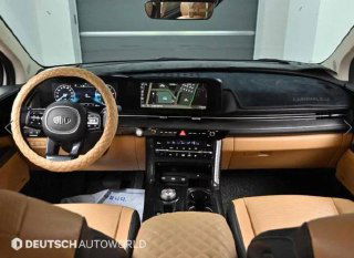 Интерьер KIA Carnival 2020 — вид на рулевую колонку и приборную панель, коричневая/бежевая отделка и мультимедиа на торпедо.