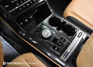 Крупный план центральной консоли KIA Carnival 2020 — селектор в виде руля, отделка под карбон и эргономика подстаканников и кнопок.