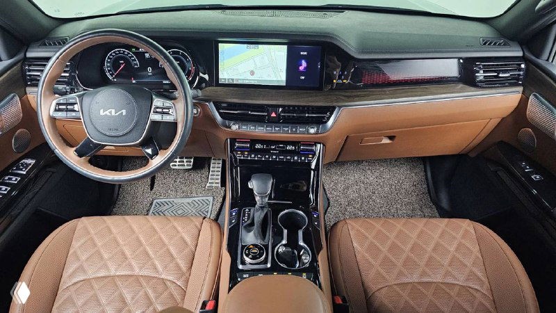 Салон KIA Mohave 2022 с коричневыми кожаными сиденьями — общий вид кабины, руль, центральная консоль и передние кресла.