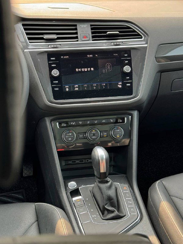 Центральная консоль Volkswagen Tiguan: мультимедийный экран, кондиционер и органы управления расположены на торпедо автомобиля, видна современная отделка.