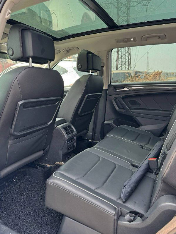 Задний ряд сидений Volkswagen Tiguan с показанным пространством для ног, подголовниками и частью багажного отделения, виден общий комфорт салона.