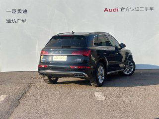Audi Q5L 2022 — вид сзади: чёрный кузов, задняя оптика и выхлопная система, автомобиль припаркован возле рекламного фона дилера.