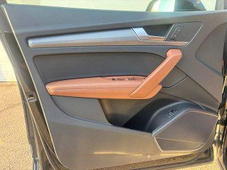 Деталь дверной карты Audi Q5L: отделка коричневой кожей, ручка двери и динамик, аккуратная заводская сборка без повреждений.