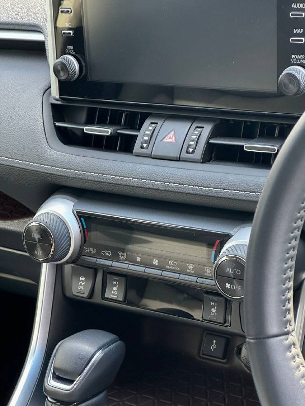 Крупный план центральной части приборной панели Toyota RAV4 2021: дисплей мультимедиа, вентиляционные решётки, органы управления климатом и отделка торпеды.