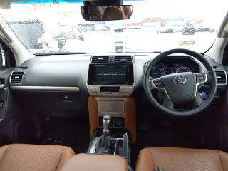 Панель приборов и центральная консоль Toyota Land Cruiser Prado 2021 с коричневой кожаной отделкой сидений и мультимедийной системой.