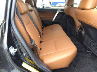 Задний ряд сидений Toyota Land Cruiser Prado 2021 с коричневой кожаной обивкой, показан простор для пассажиров и состояние кресел.